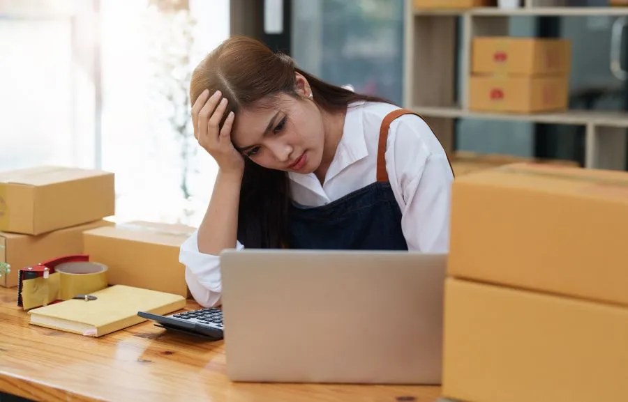 A warehouse employee, looking at the computer with sadness..
