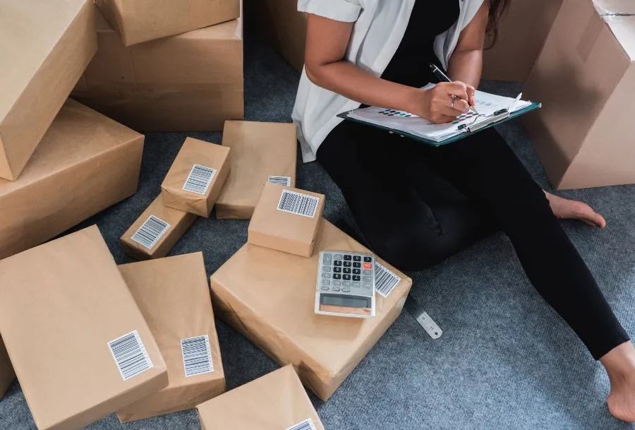 Merchant who is sitting with inventory boxes and planning inventory.