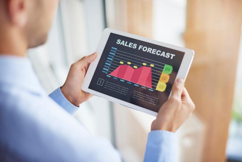 A businessman checks the sales forecast on his tablet.