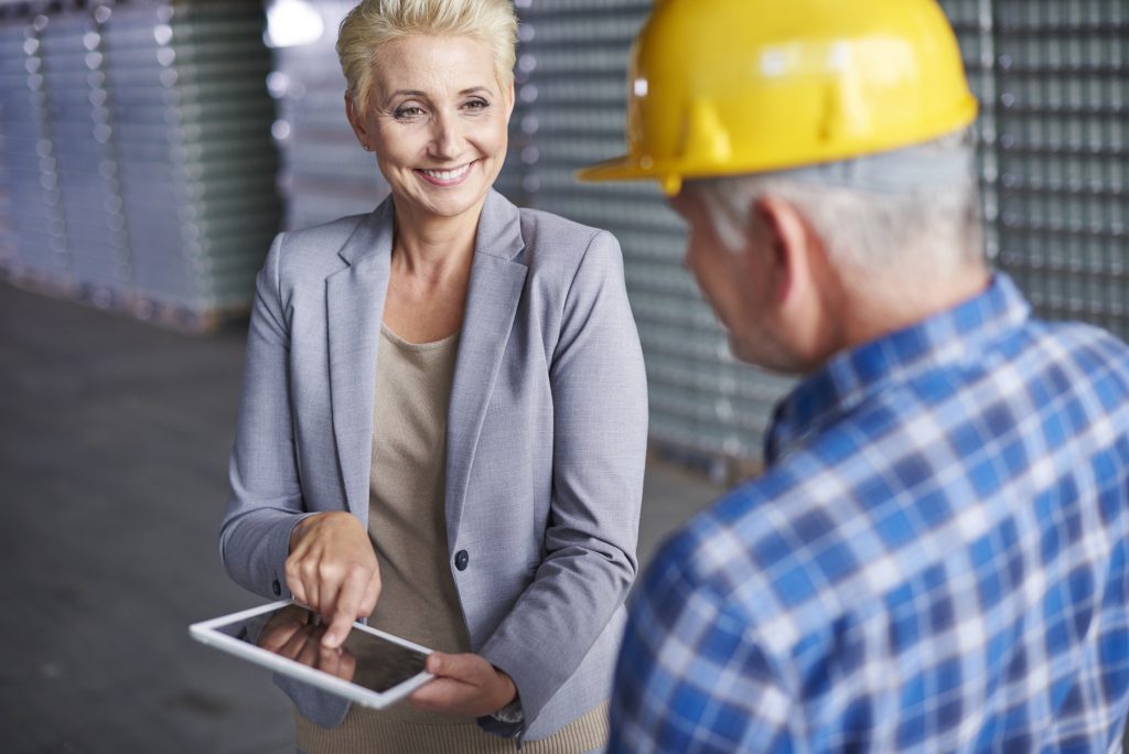 Picture of a woman manager speaking with an employee in warehouse..
